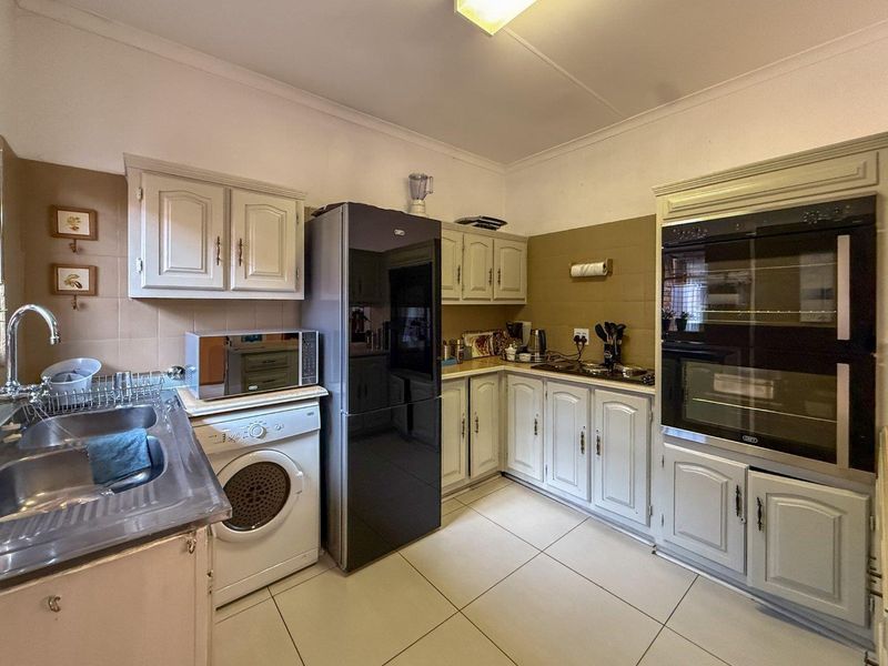 A functional kitchen featuring built-in cabinetry, a double oven, hob, and tiled flooring with a neutral backsplash.