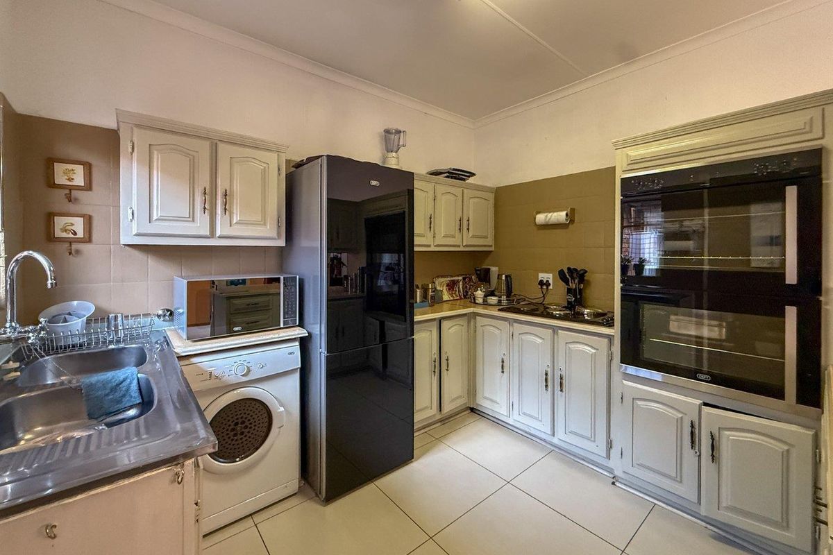 A functional kitchen featuring built-in cabinetry, a double oven, hob, and tiled flooring with a neutral backsplash.