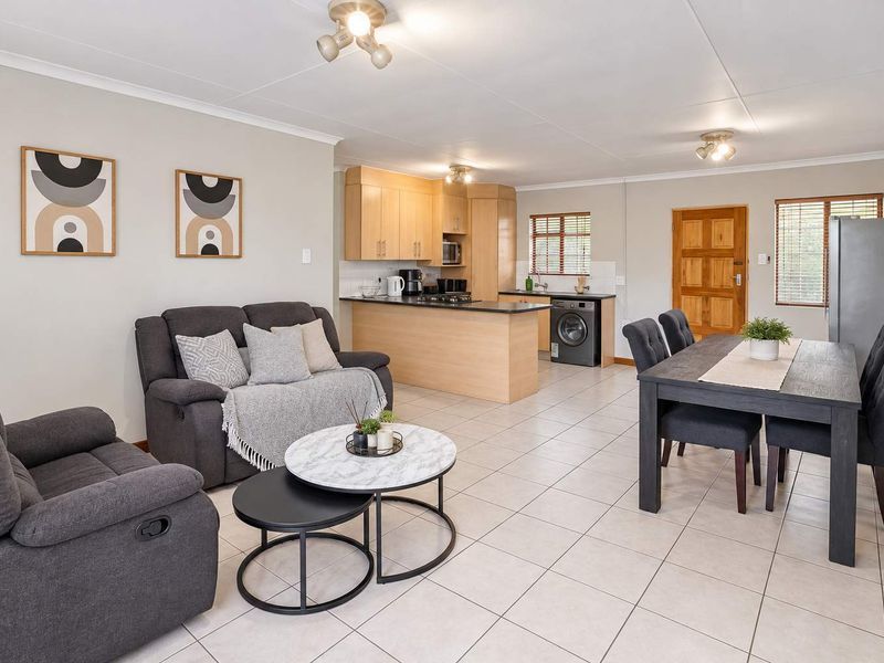 Open-plan living and dining area featuring tiled floors and a functional kitchen with built-in cabinetry and appliances.