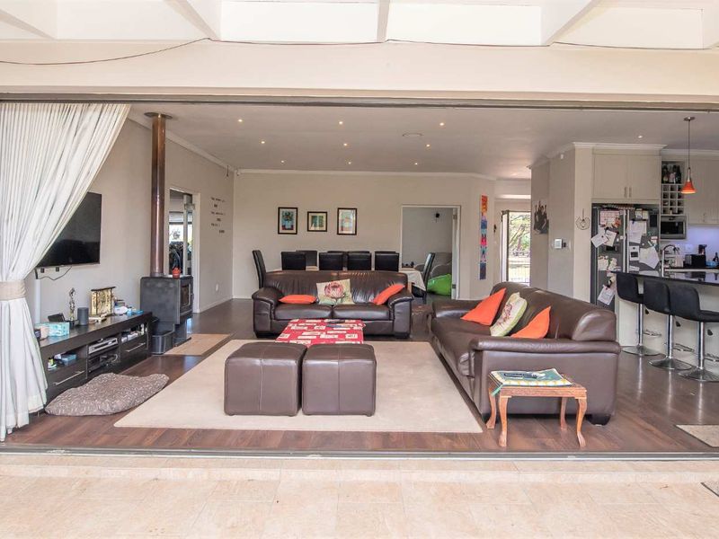 Spacious open-plan living area featuring a modern kitchen with island, wood-burning fireplace, and seamless flow to a tiled patio through large bi-fold doors.