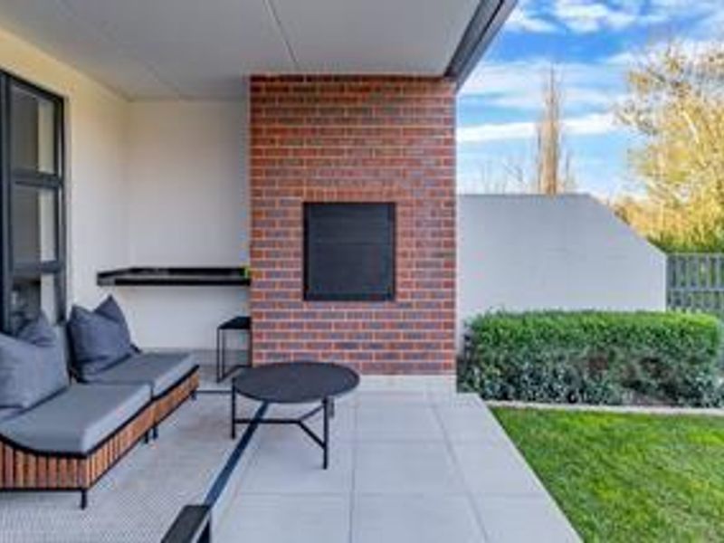 Covered patio area featuring a brick fireplace, tiled flooring, and direct access to the garden through large sliding glass doors.