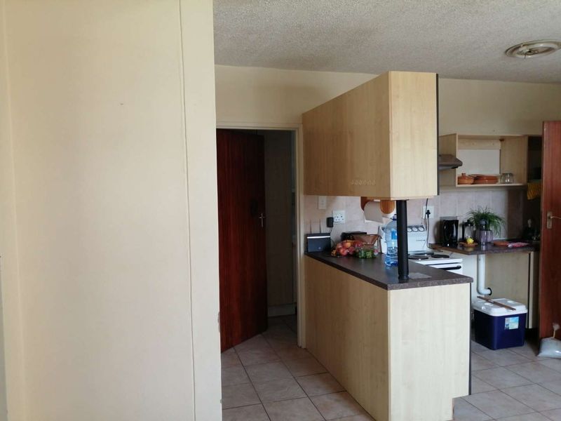 A dated kitchen featuring laminate cabinetry, tiled flooring, and a breakfast bar counter, offering potential for a modern renovation.