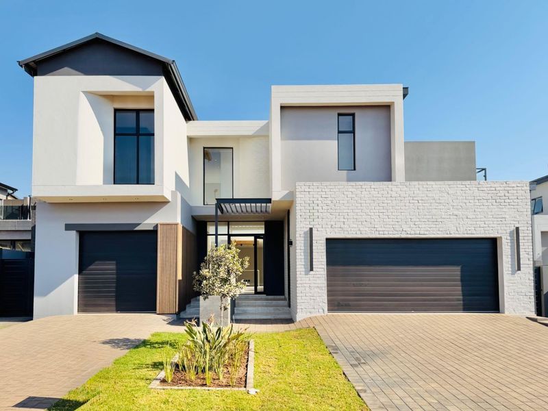 Modern double-story residential home featuring a contemporary facade, brick detailing, paved driveway, and integrated garage doors.