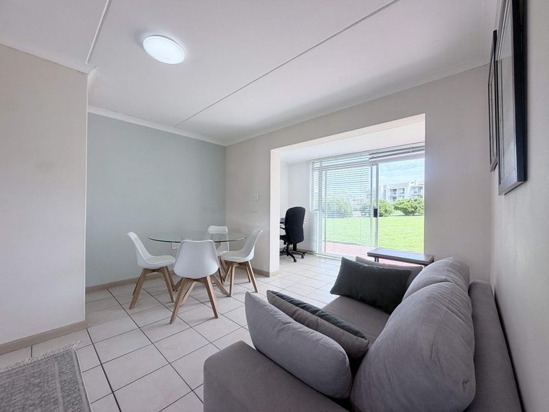 Open plan living and dining area featuring tiled flooring, neutral walls, and a sliding glass door providing access to the exterior.