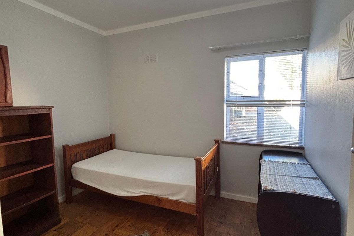A bedroom featuring classic parquet flooring, a central ceiling light, and a window with fitted blinds.