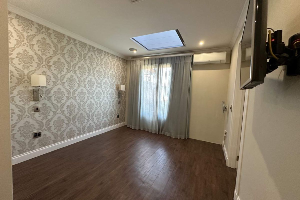 A well-maintained bedroom featuring wood-look flooring, a skylight, wall-mounted lighting, and a split-system air conditioning unit.