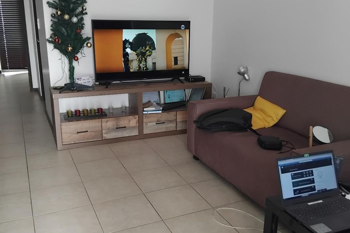 A living room area featuring neutral floor tiles and a clear transition into the hallway.