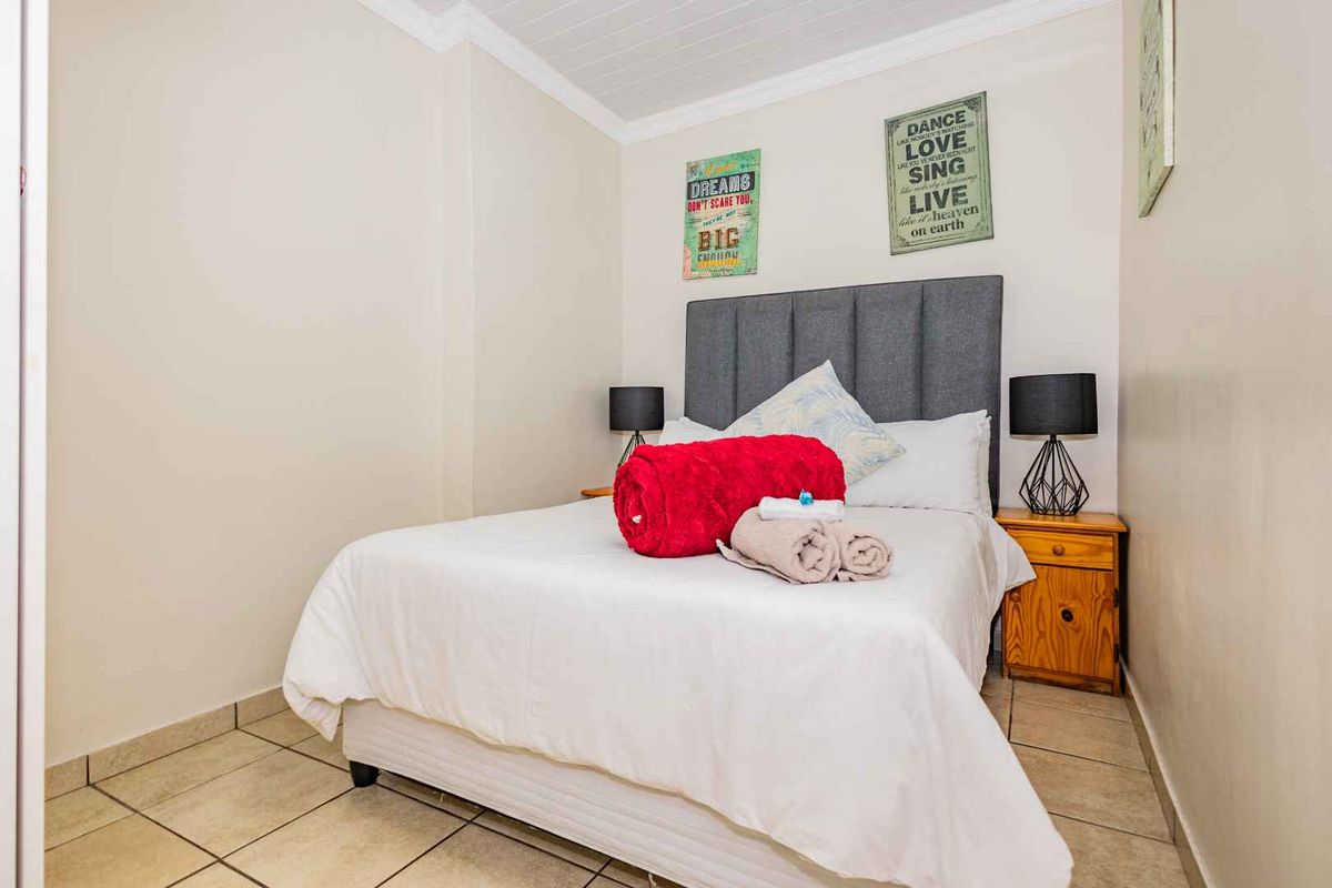 A compact bedroom featuring tiled flooring and a neutral color palette, providing a functional and comfortable sleeping space.