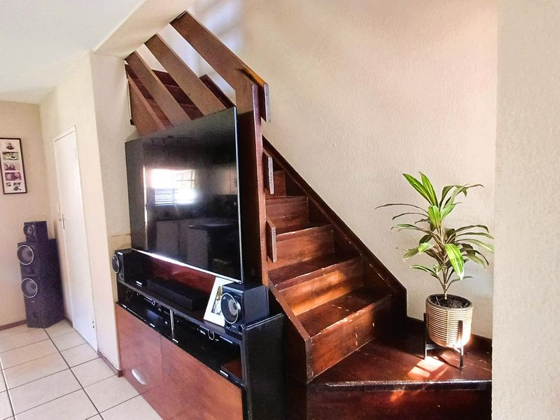 Living area featuring a wooden staircase with integrated storage space and tiled flooring throughout.