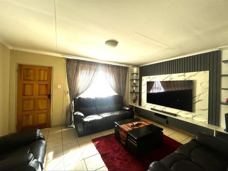 A comfortable living room featuring a modern built-in media wall with marble-look paneling and tiled flooring.