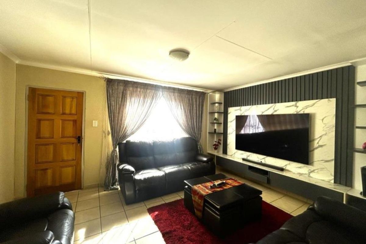 A comfortable living room featuring a modern built-in media wall with marble-look paneling and tiled flooring.