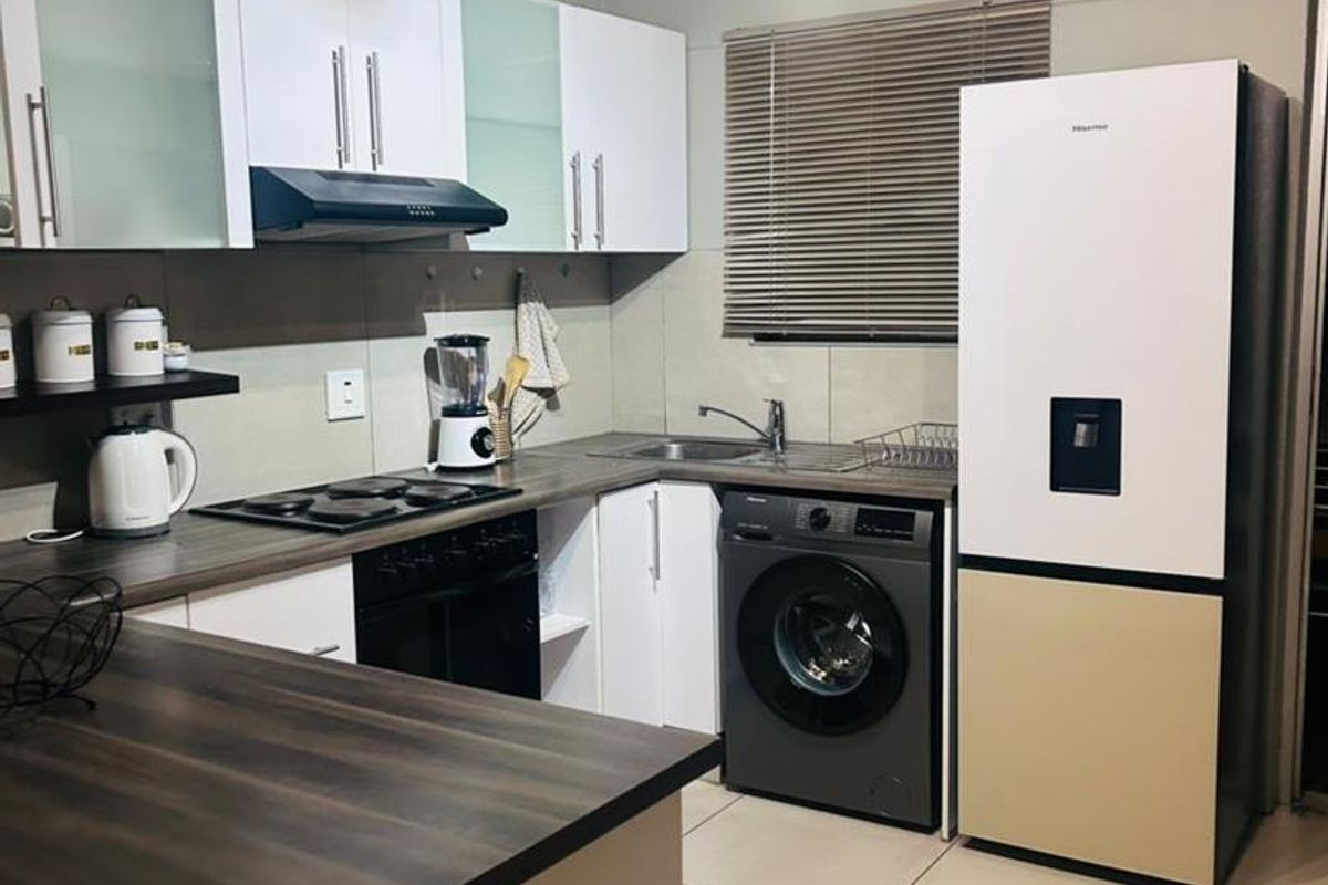Modern kitchen featuring white cabinetry, dark wood-look countertops, integrated hob and oven, and tiled flooring with a functional layout.