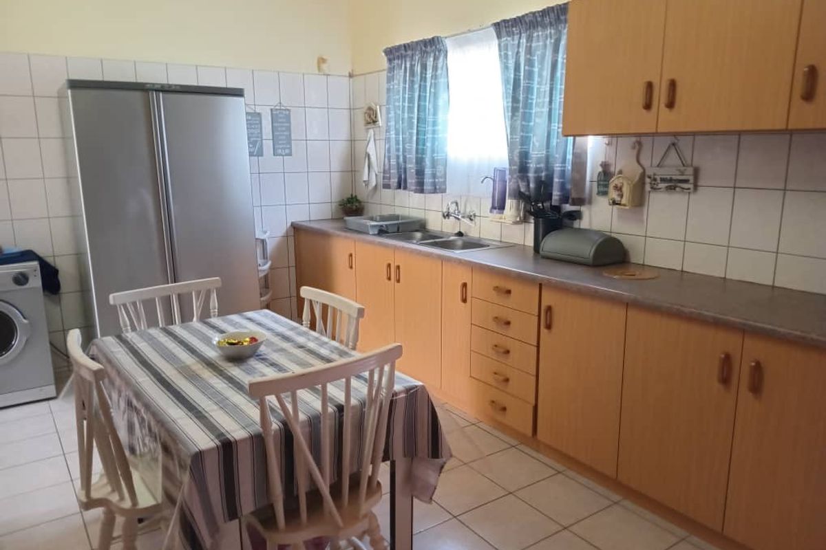 A functional kitchen featuring light wood-tone cabinetry, tiled splashbacks, a double-basin sink, and tiled flooring.