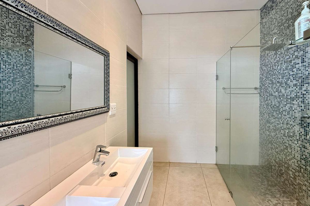 Modern bathroom featuring a double vanity, large framed mirror, and a spacious walk-in shower with a mosaic tile accent wall.