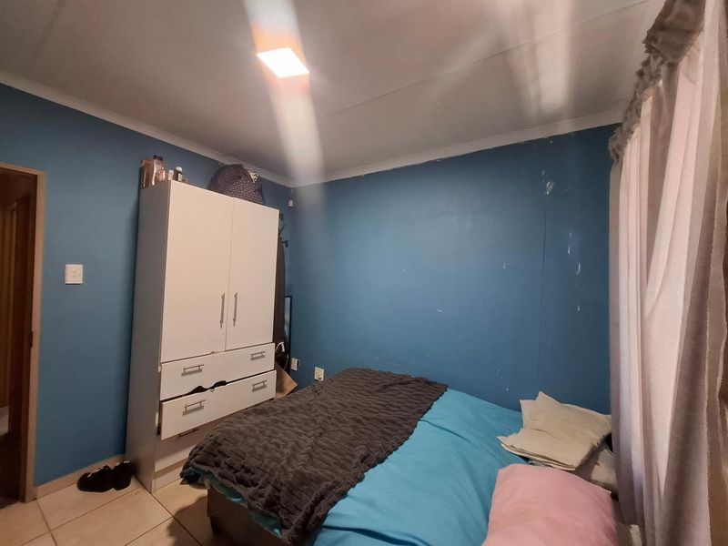 A bedroom featuring tiled flooring and blue painted walls with visible signs of wear and scuffing.