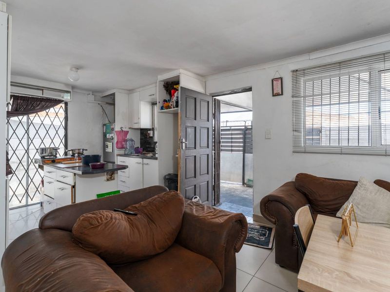 Open-plan living and kitchen area featuring tiled floors, built-in cabinetry, and direct access to an outdoor patio through a security gate.