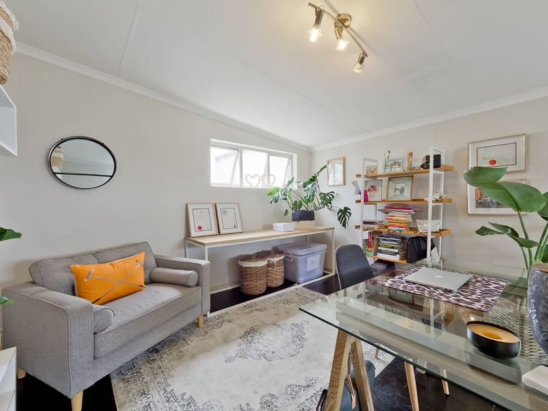 A bright and functional home office space featuring neutral wall finishes, an awning window, and modern ceiling-mounted spotlighting.