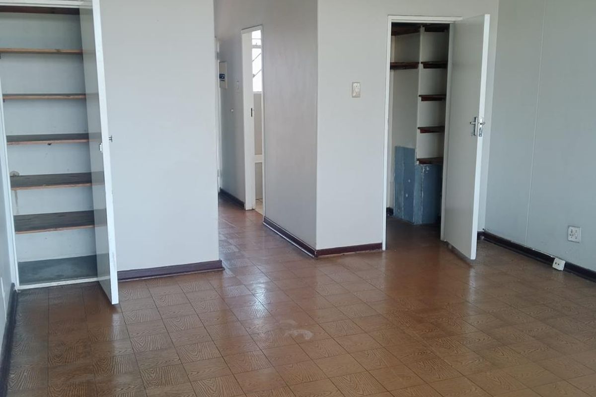 An empty bedroom featuring built-in storage cupboards and vinyl tile flooring, offering a blank canvas for renovation or interior design updates.
