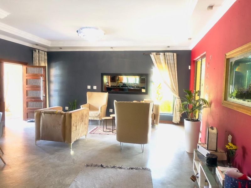 Spacious living room featuring polished concrete flooring, decorative crown molding, and a bold accent wall, providing a versatile area for relaxation.