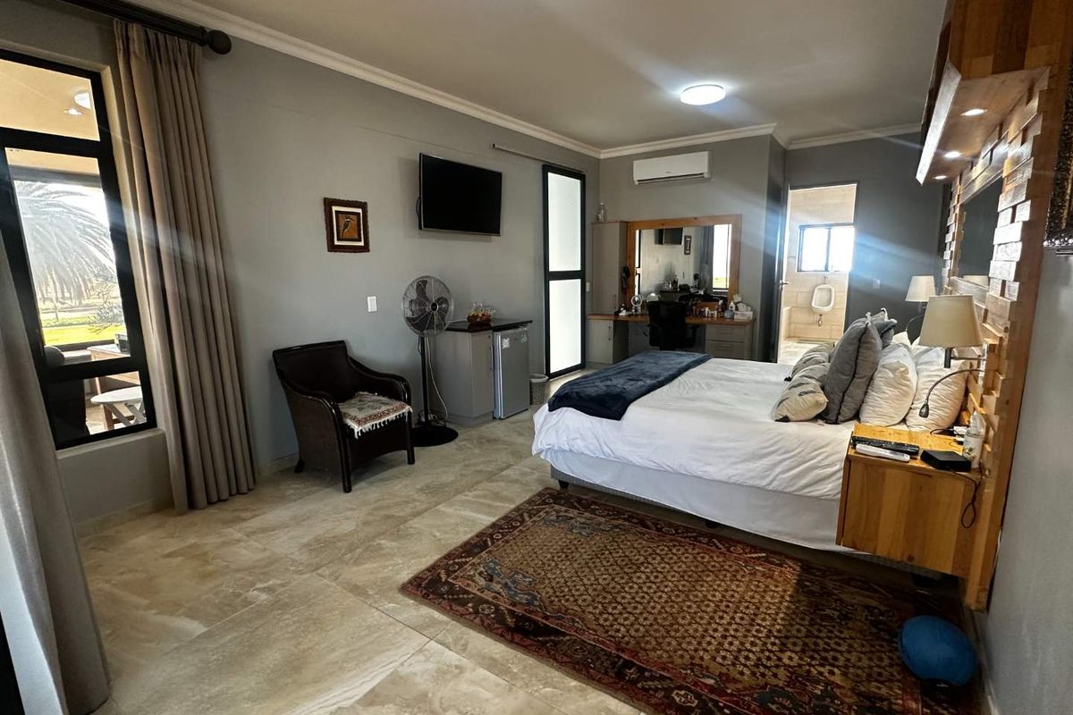 Spacious bedroom featuring large format floor tiles, split-system air conditioning, built-in vanity, and direct access to an en-suite bathroom.