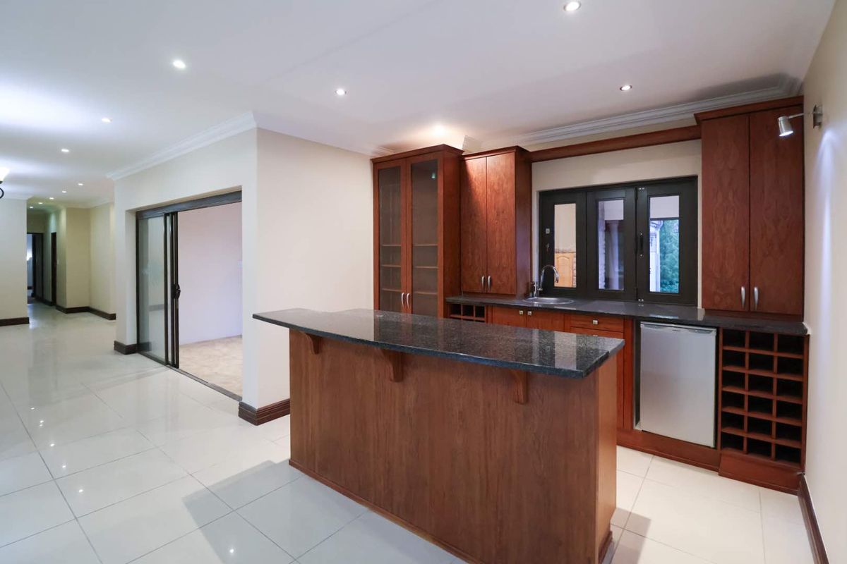 A clean, modern kitchen featuring dark wood cabinetry, granite countertops, tiled floors, and recessed lighting, with an open-plan layout and sliding door access.