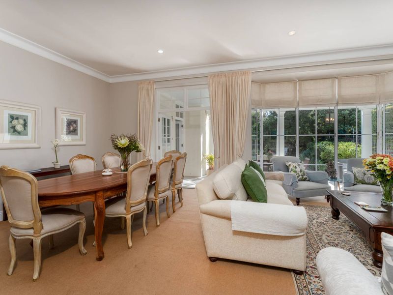 Spacious open-plan living and dining area featuring large windows, recessed lighting, and direct access to the outdoor patio through classic french doors.