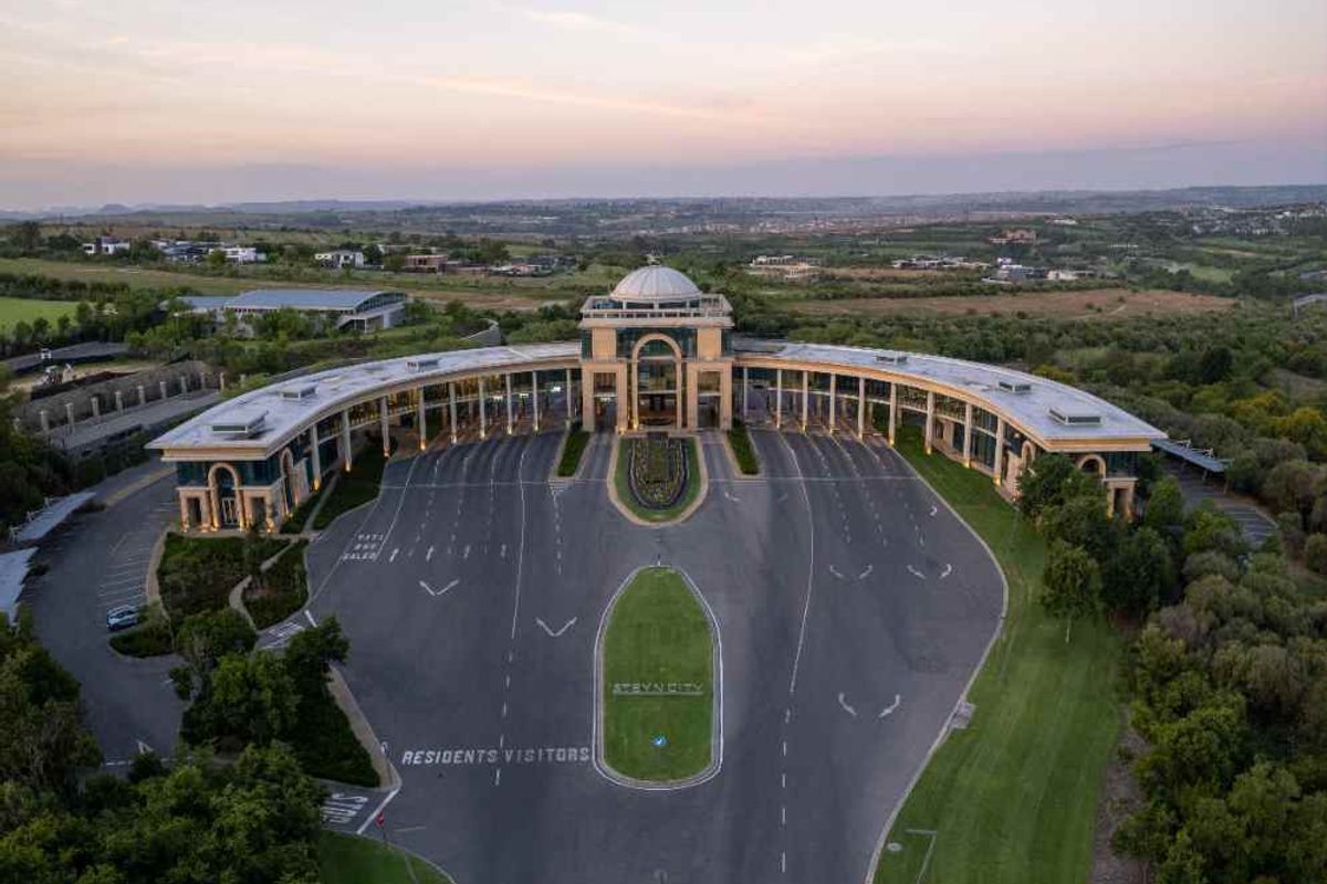 Aerial view of the grand entrance and driveway of Steyn City, showcasing the expansive landscaped grounds and architectural facade.