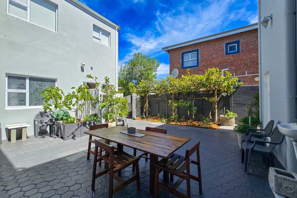 A paved rear courtyard area featuring a built-in outdoor basin, established vine trellises, and perimeter boundary walls.