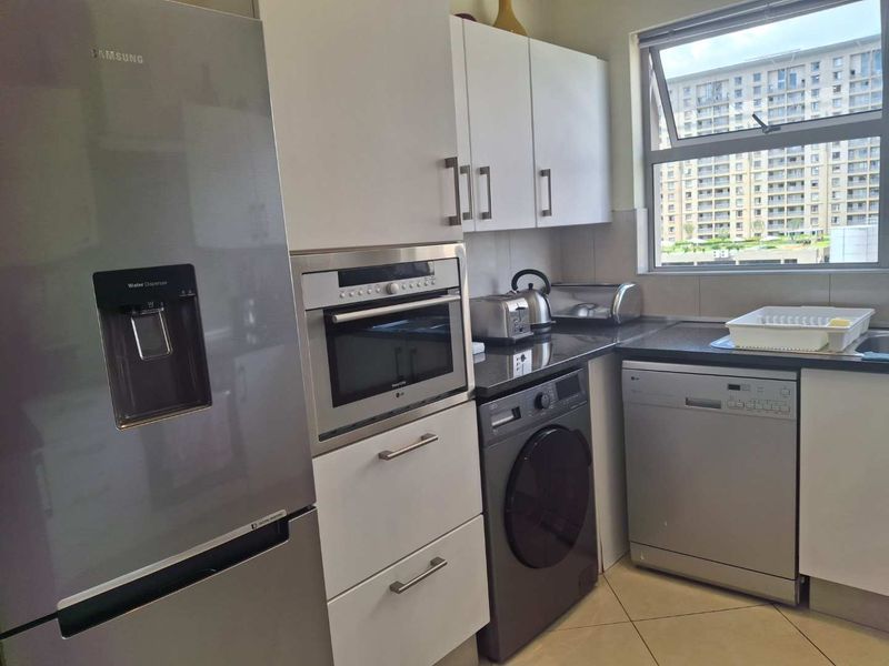 A functional kitchen featuring granite countertops, built-in oven, and ample cabinetry, with tiled flooring and a window providing natural light.