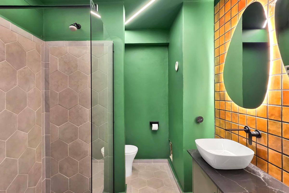 Modern bathroom featuring a walk-in shower with hexagonal tiling, a wall-mounted toilet, and a stylish vanity with a vessel sink and backlit mirror.