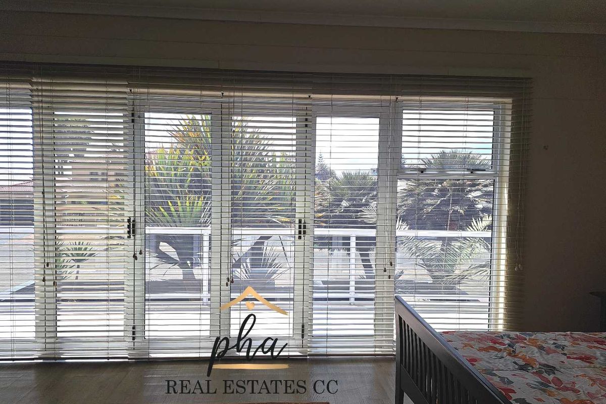 Bedroom featuring large glass sliding doors with integrated blinds, providing access to an outdoor balcony area.