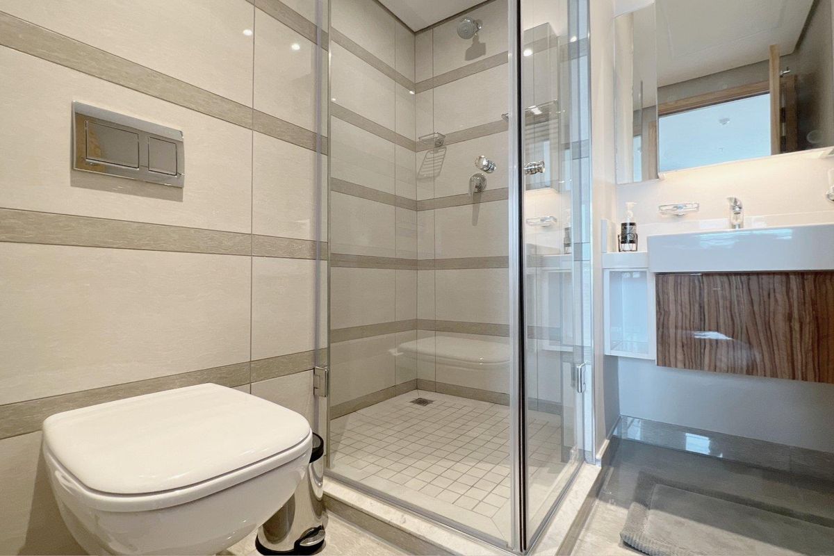 Modern bathroom featuring a glass-enclosed shower, wall-mounted toilet, and a contemporary vanity basin with tiled wall finishes.