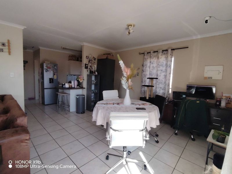 Open plan living and dining area featuring tiled flooring and an integrated kitchen space with a breakfast counter.