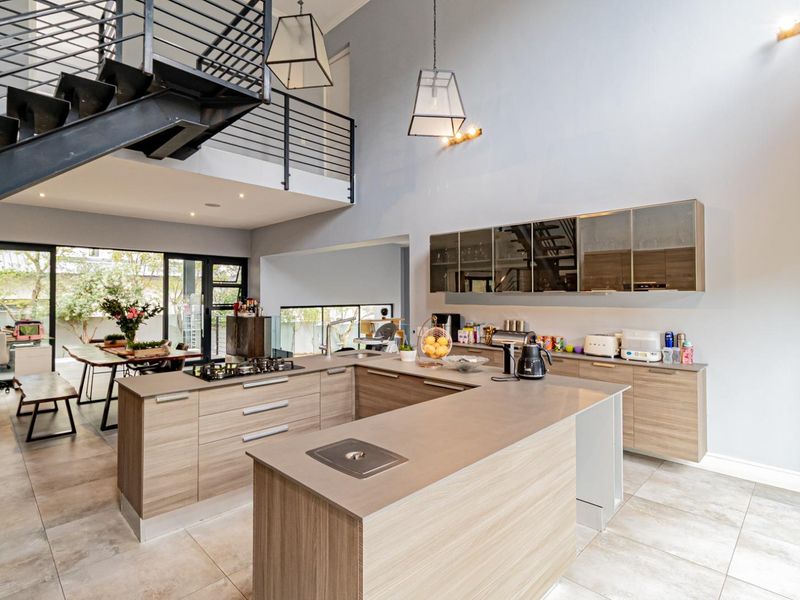 Spacious open-plan kitchen featuring modern cabinetry, a central island with a gas hob, and a striking metal staircase leading to a mezzanine level.