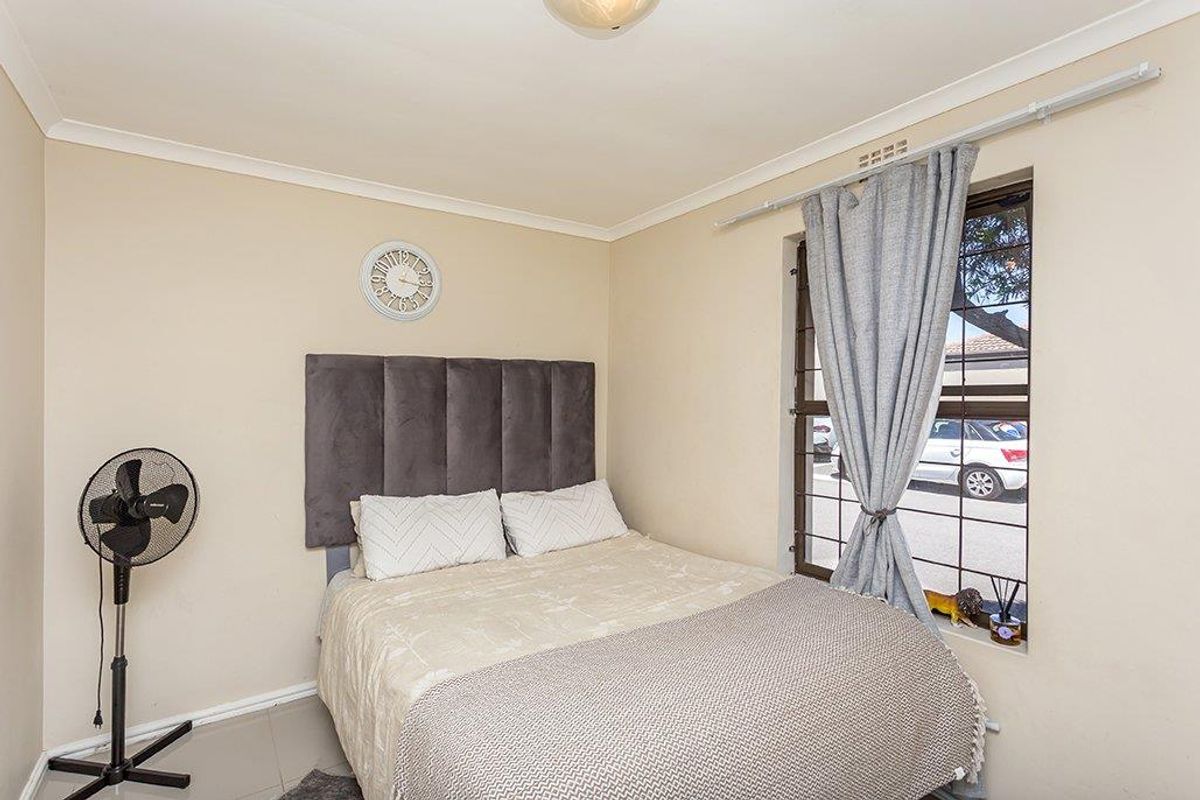 A functional bedroom featuring tiled flooring, cove cornicing, and security bars on the window for added peace of mind.