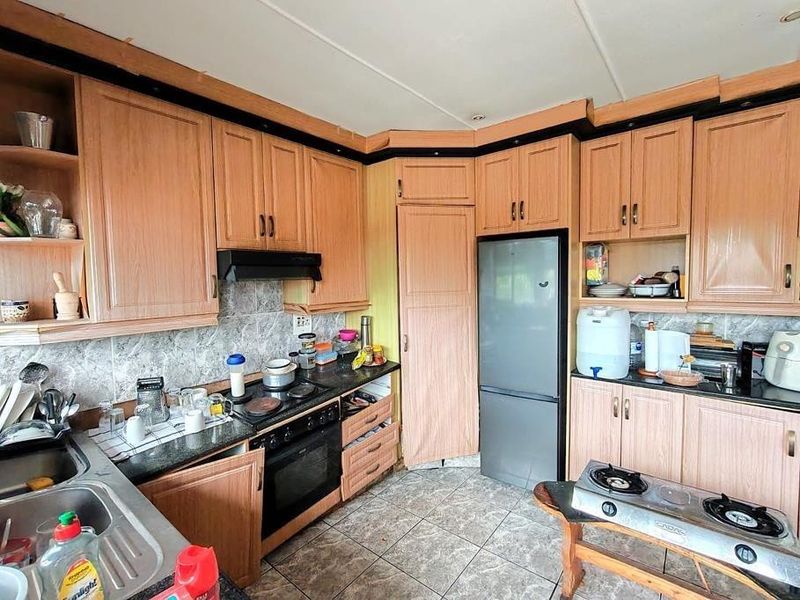 A functional kitchen featuring wood-look laminate cabinetry, a built-in oven with extractor fan, tiled backsplash, and tiled flooring.