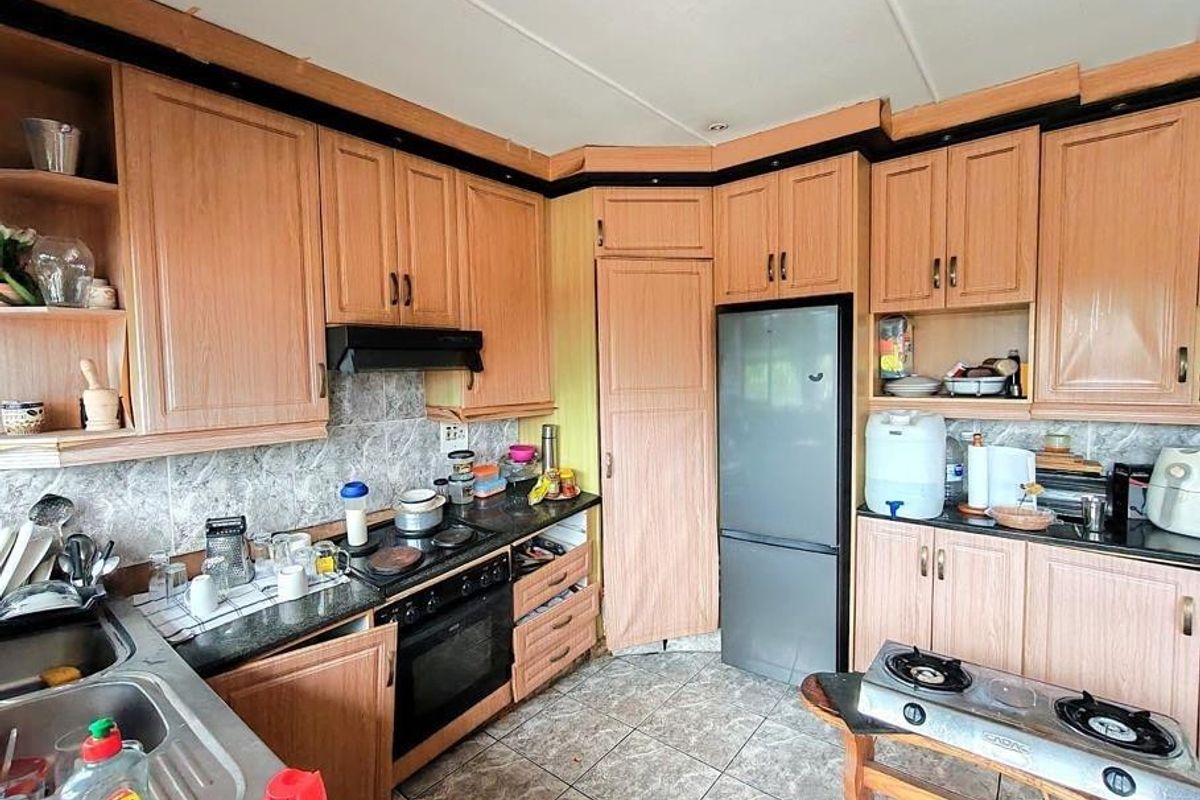 A functional kitchen featuring wood-look laminate cabinetry, a built-in oven with extractor fan, tiled backsplash, and tiled flooring.