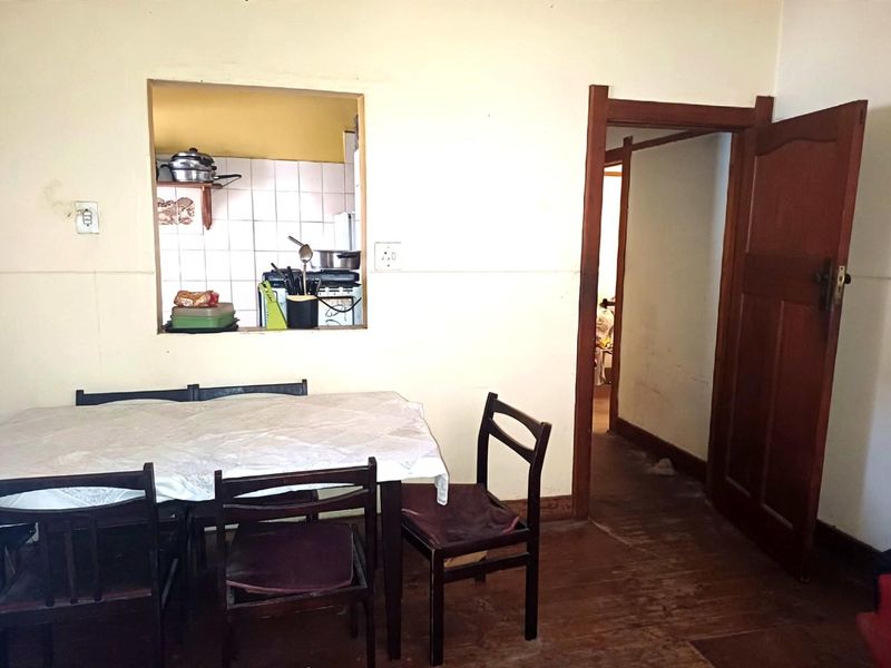 Dining area featuring a serving hatch to the kitchen, original timber flooring, and a classic wooden door leading to the hallway.