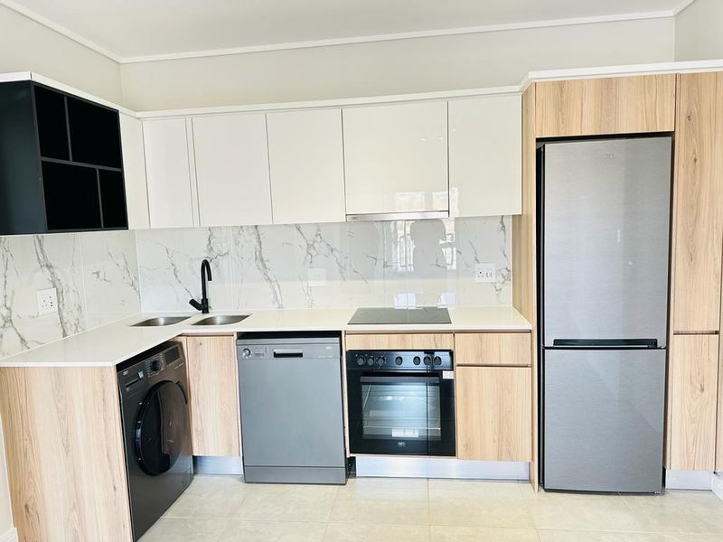 Modern kitchen featuring sleek white and wood-grain cabinetry, marble-look splashback, integrated appliances, and high-quality finishes throughout.