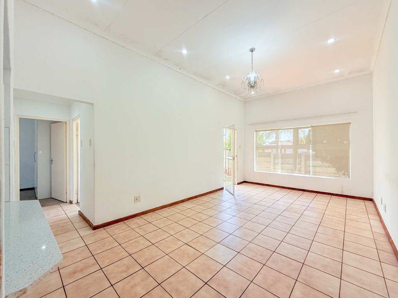 Spacious, empty living area featuring tiled flooring, recessed lighting, and a security gate, with visible ceiling maintenance required.
