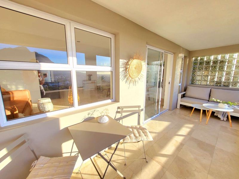 A bright, covered patio featuring tiled flooring, a decorative glass block wall, and large sliding doors providing seamless indoor-outdoor flow.