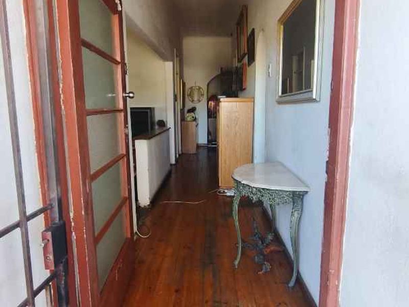 Entrance hallway featuring original timber flooring and a classic transom window above the doorway, leading into the main living area of the home.