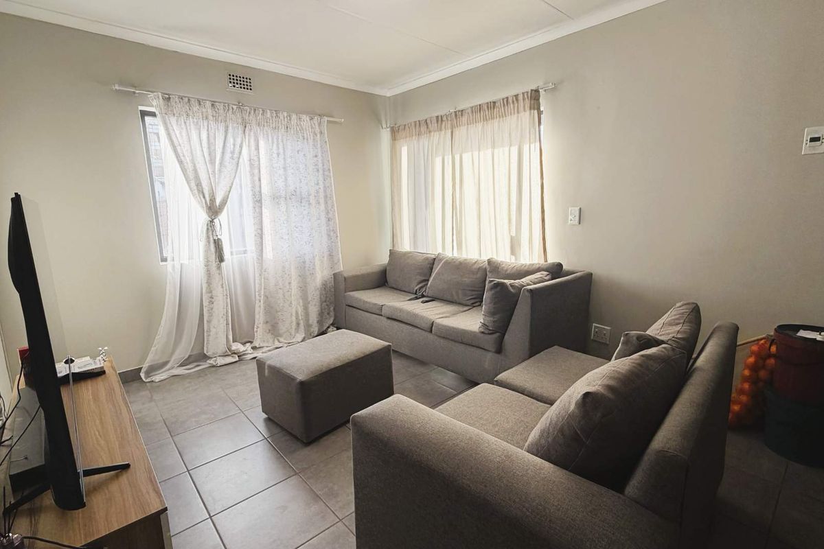 A comfortable living room featuring neutral tiled flooring and large windows that allow for ample natural light.