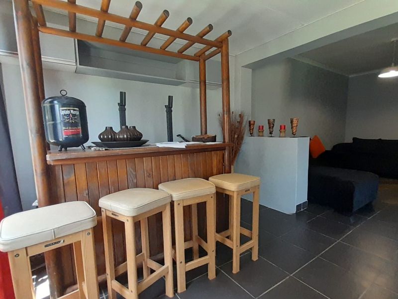 A dedicated bar area featuring a built-in wooden bar counter and tiled flooring, seamlessly integrated into the living space.