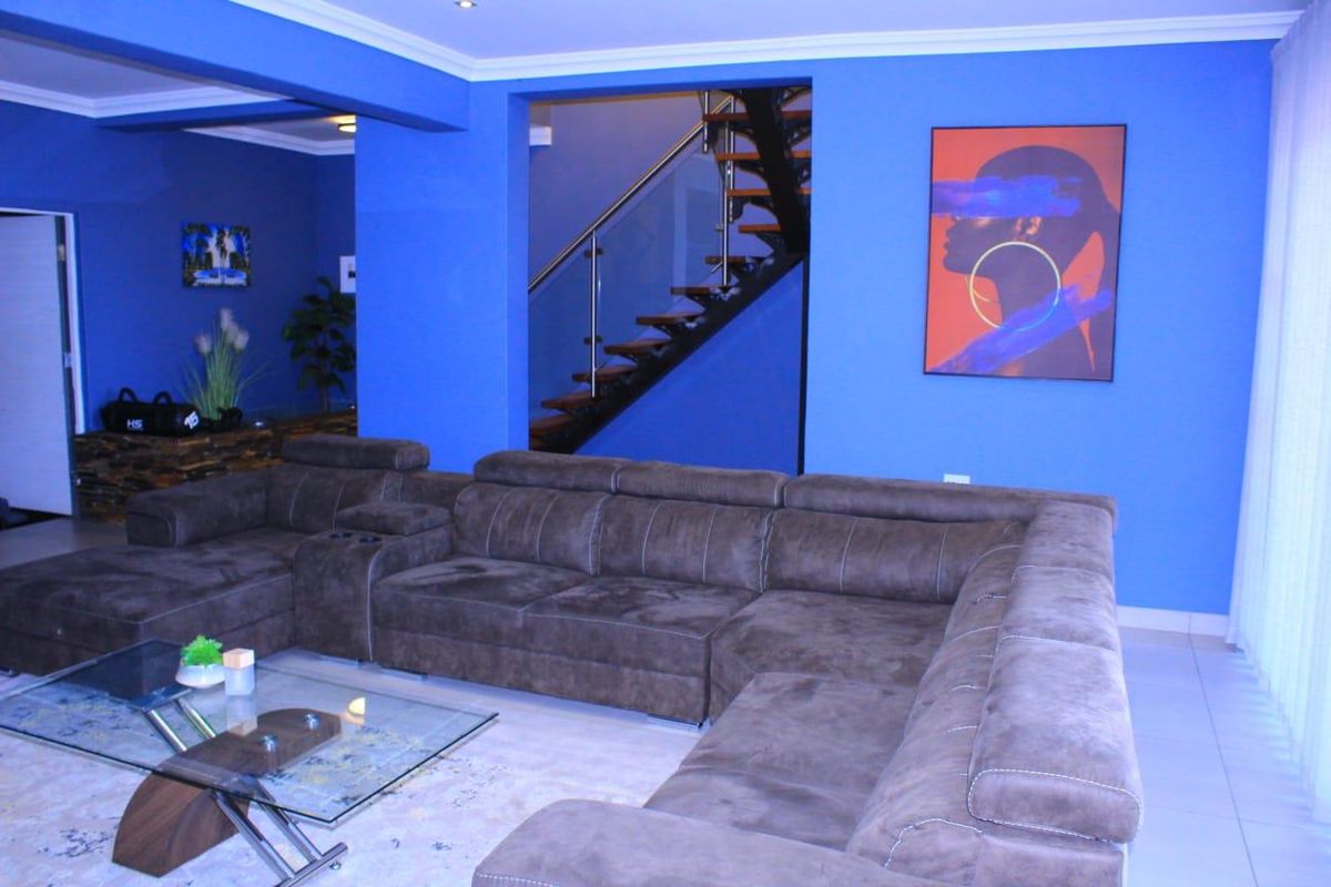 Spacious living area featuring a modern floating staircase with glass balustrades and bold blue accent walls.