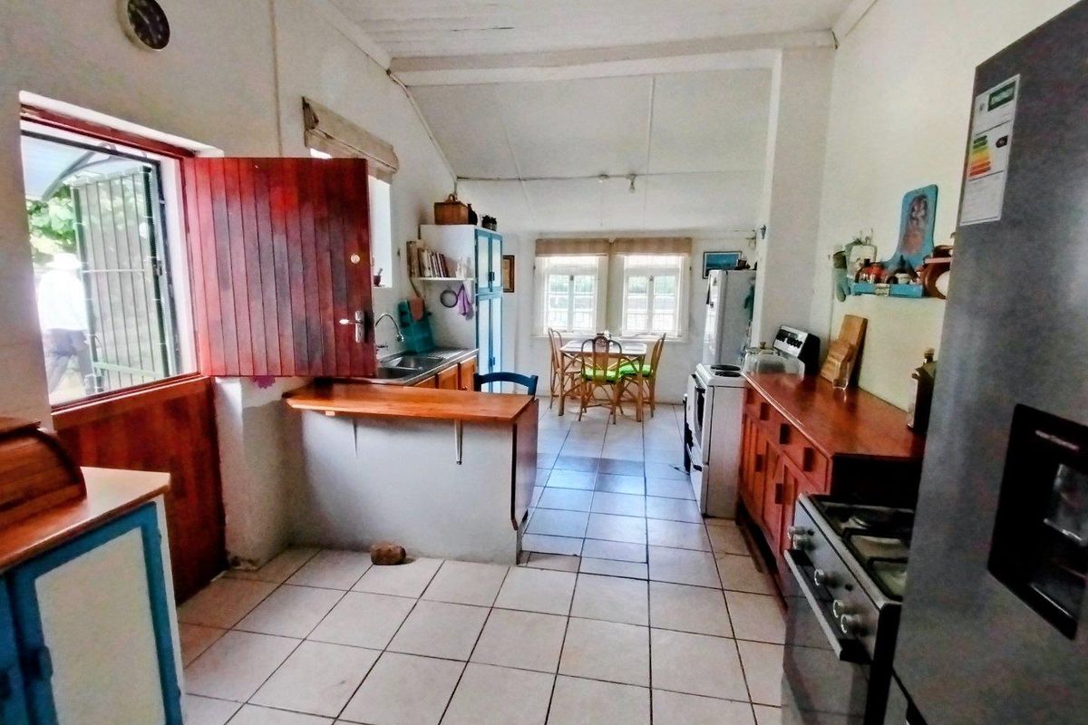 A dated kitchen featuring tiled flooring, wooden cabinetry, and a breakfast bar, with direct access to the exterior through a side door.