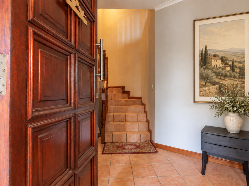 Welcoming entrance foyer featuring a solid timber front door, ceramic tiled flooring, and a staircase with a traditional timber balustrade.