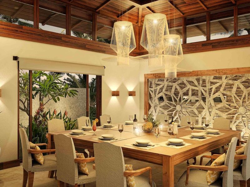 Elegant dining room featuring a decorative stone feature wall, exposed timber ceiling beams, and large sliding glass doors opening to a private garden.