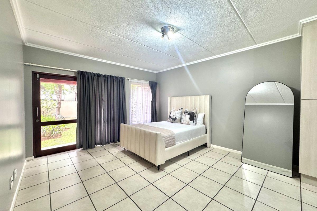 Spacious bedroom featuring tiled flooring, a drop ceiling, and direct access to the garden through a glass sliding door.