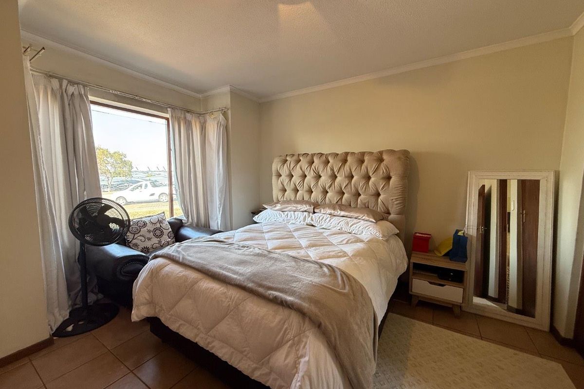 A bedroom featuring tiled flooring and a large window allowing natural light, providing a comfortable and functional living space.